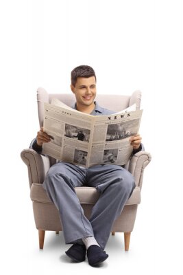 Młody chłopak czytający książkę w wygodnym fotelu po południu